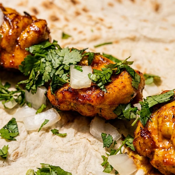 Chicken tikka skewer with cilantro and onions on a flatbread.